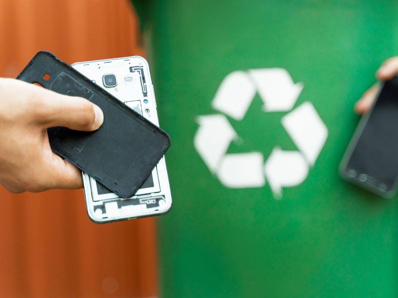 mobile phone in hand near recycling bin