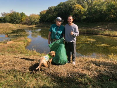 People clean up litter at the edge of a body of water